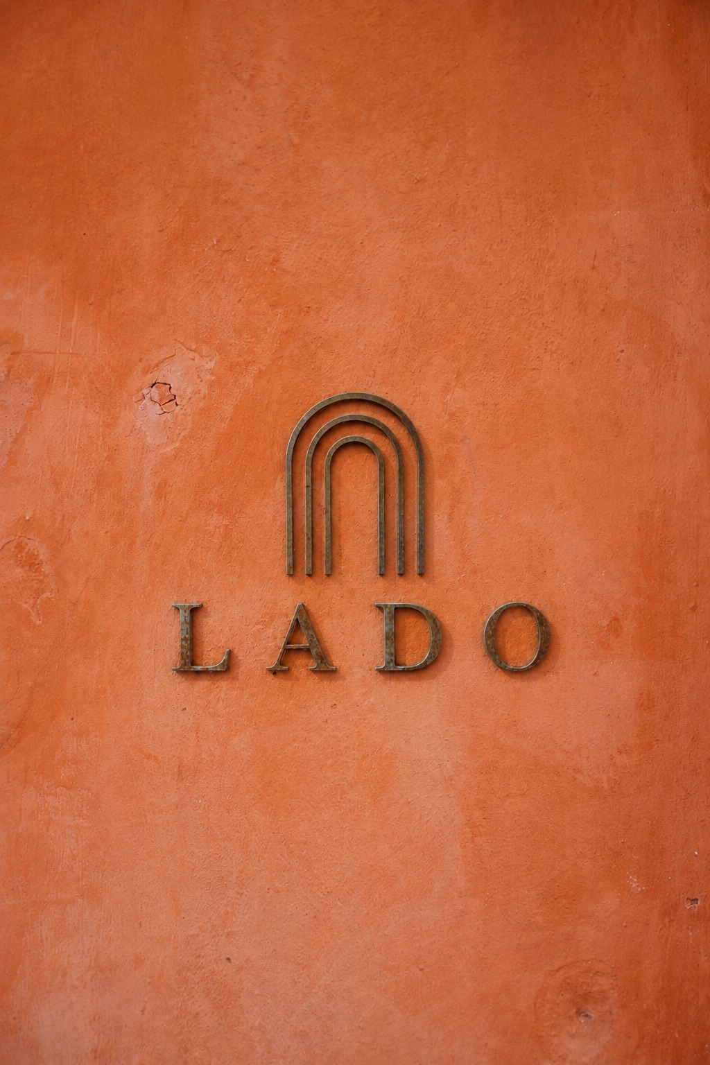 LADO wordmark embossed on a terracotta wall